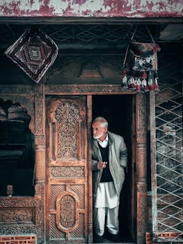 一位老人的肖像挂在一扇雕刻精美的木门旁，展现了传统文化的韵味