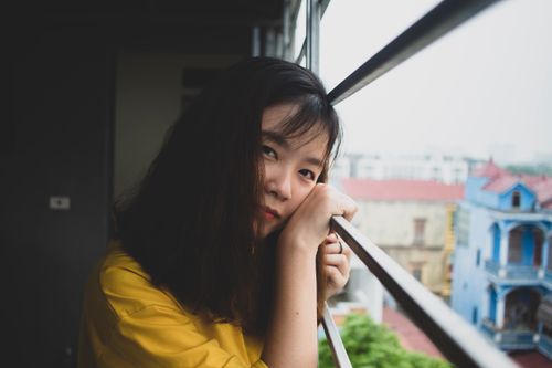 Free Portrait of a young woman gazing out a window, capturing a serene moment in Hanoi, Vietnam. Stock Photo