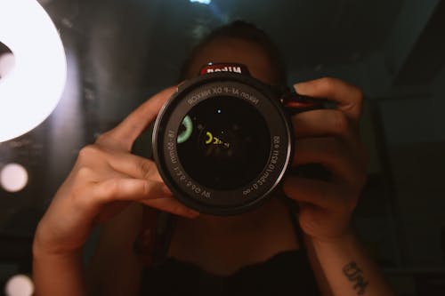 Persona Sosteniendo Una Cámara Dslr Negra Y Roja Con Ambas Manos