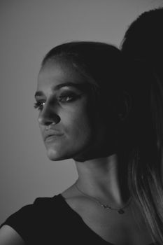 High contrast monochrome portrait showcasing a woman's side profile in a shadowy setting.