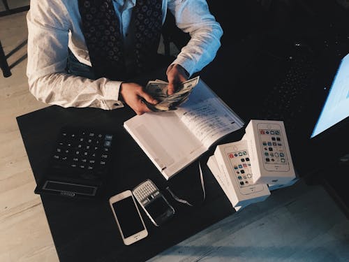 Person, Die Geld Mit Smartphones Vor Auf Schreibtisch Zählt