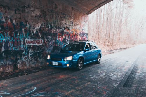 Free Blue car under graffiti-filled tunnel in Williamsburg, Virginia Stock Photo