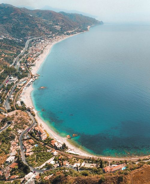 Free Stunning aerial view of Taormina's coastline in Sicily showcasing the turquoise sea and coastal scenery. Stock Photo