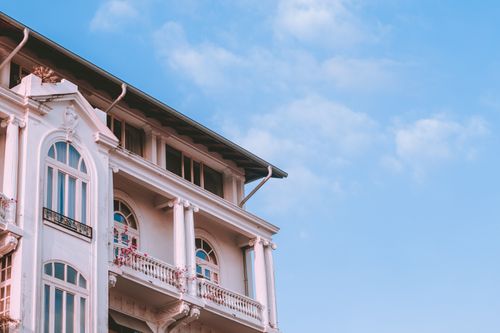 Free A charming neoclassical building facade against a vibrant blue sky, showcasing architectural elegance. Stock Photo