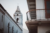 白天，城市阳台设有华丽的栏杆，位于乡村教堂塔楼旁边