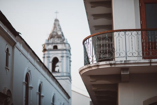白天，城市阳台设有华丽的栏杆，位于乡村教堂塔楼旁边