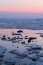 日落时分，冰冻海岸一片宁静，粉红与蓝色的色调映照在平静的水面上