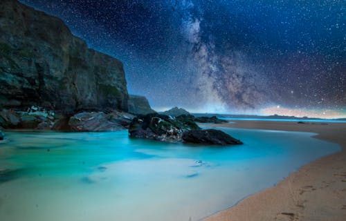 Океан со скальными образованиями под звездной ночью