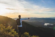 日出时分，一名背着背包的男子欣赏着周围环绕着大自然的广阔山景