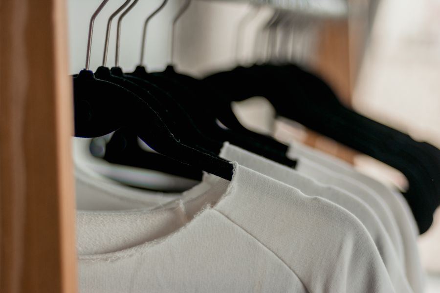 Plain white t-shirts hanging on a rack, the kind of blank canvas print-on-demand sellers add designs to