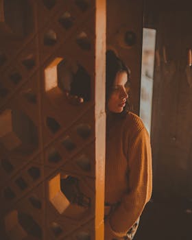 一个女人穿着舒适的毛衣，倚在几何墙壁上，营造出喜怒无常的氛围