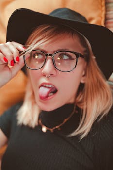 一张时尚女性的特写肖像，她戴着黑色帽子和眼镜，表情俏皮