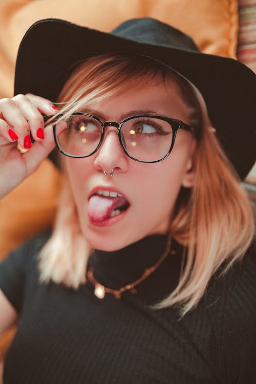 Photo of Woman In Black Hat and Top Sticking Her Tongue Out