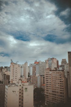 在戏剧性的多云天空下，城市天际线中的摩天大楼展示了现代建筑