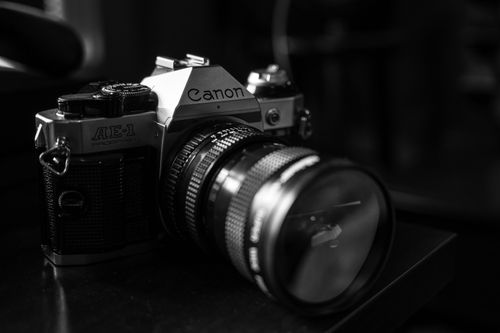 Free Close-up of a classic Canon AE-1 camera with a focus on the lens in monochrome. Stock Photo
