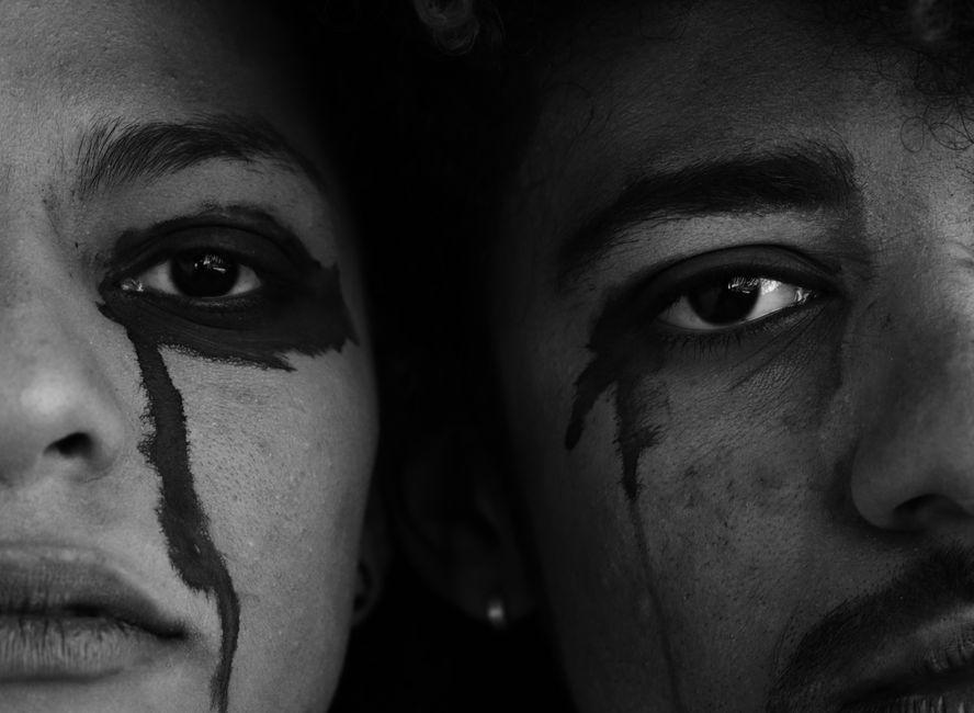 Close-up black and white portrait showing emotional expressions with face paint on two individuals.