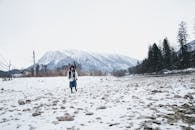 一名妇女走过白雪皑皑的奥地利巴德戈伊森，背景是山脉和树木