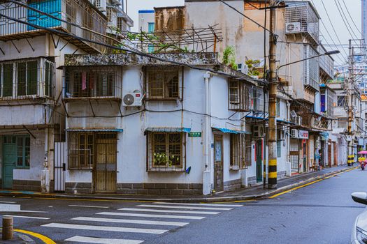 A vibrant urban street corner showcasing rustic architecture and pedestrian crossing on a rainy day.