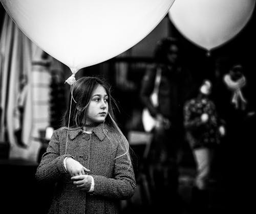 A girl holding a balloon in front of a crowd