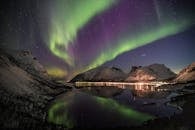 夜晚，北极光在雪山与倒影的河流上翩翩起舞，令人惊叹