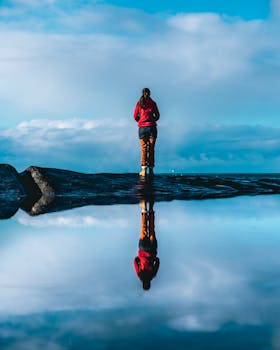 一名女子站在反光的水面旁，头顶是充满活力的蓝天，象征着宁静