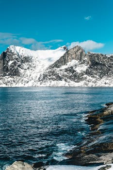 冬日天空明亮，湖水清澈湛蓝，映衬着白雪皑皑的山脉