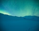 在星空下，迷人的北极光照亮了白雪皑皑的山脉