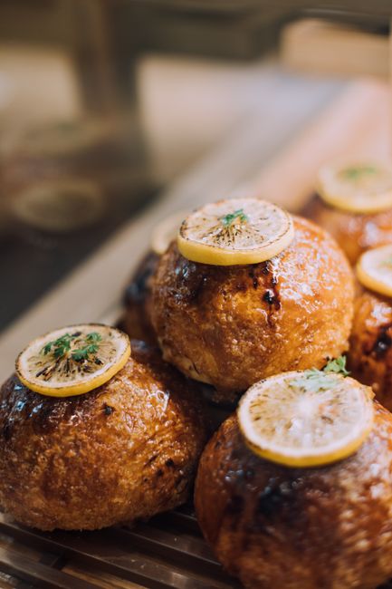 Close-up of delicious lemon-glazed roasted meatballs garnished with herbs.