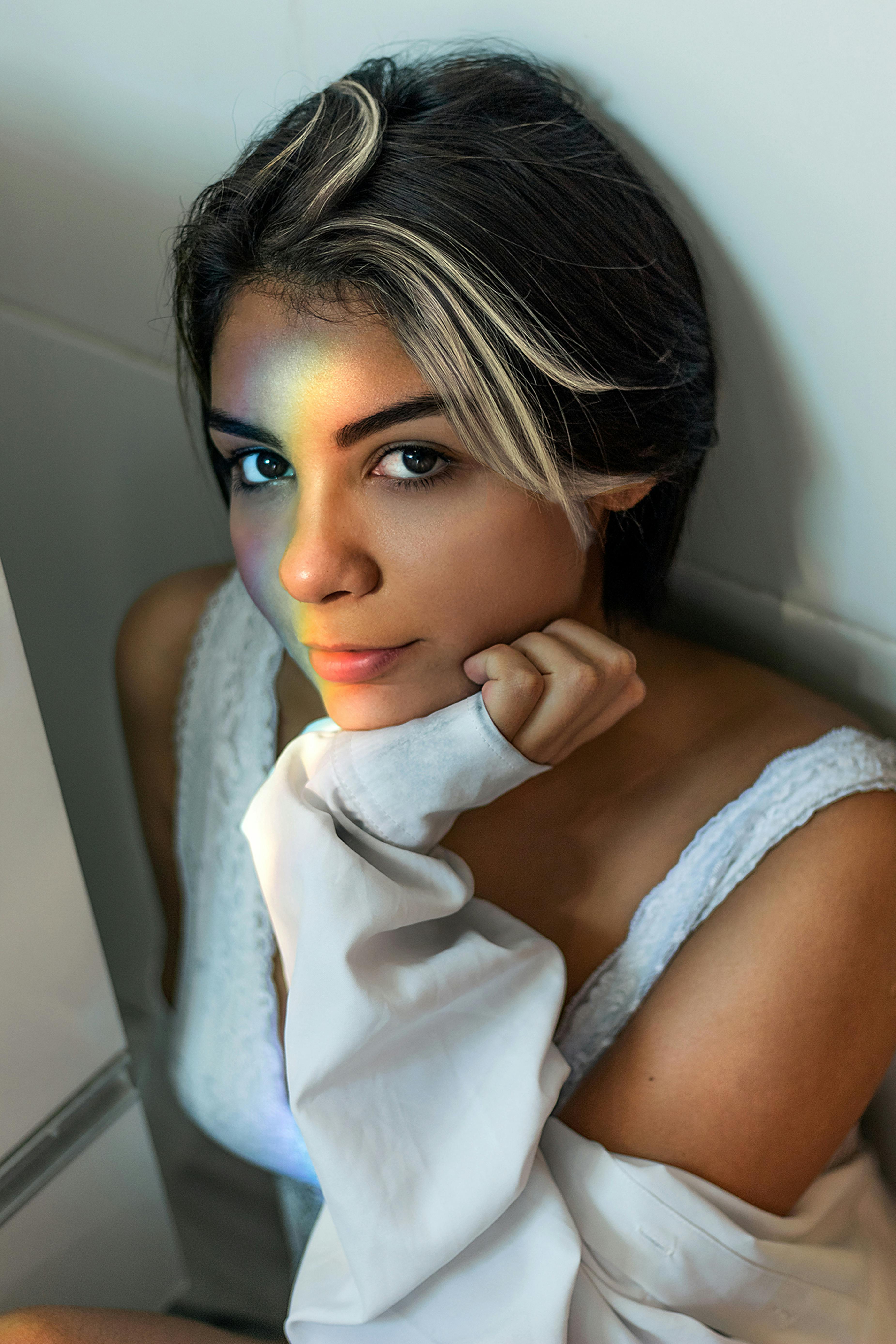 一位女子脸上映着彩虹光芒的特写肖像，散发着美丽与优雅