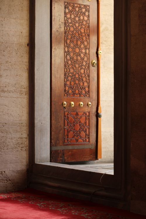 Free Intricately carved wooden door with a red carpet entrance in a historic building. Stock Photo