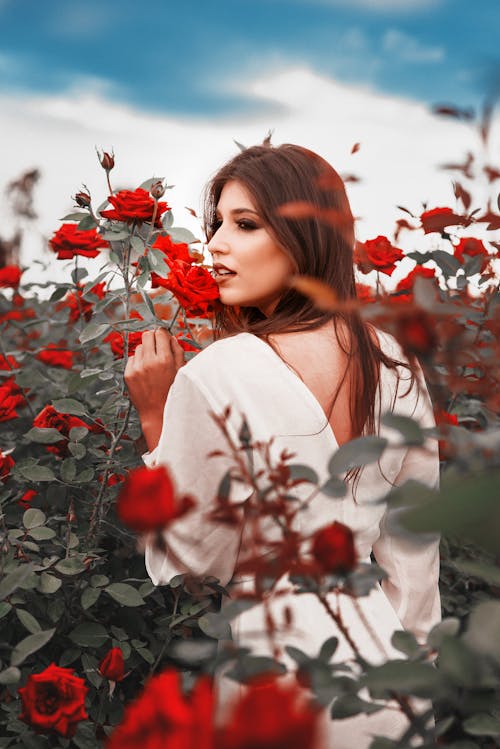 Фотография женщины в белом платье в окружении красных роз