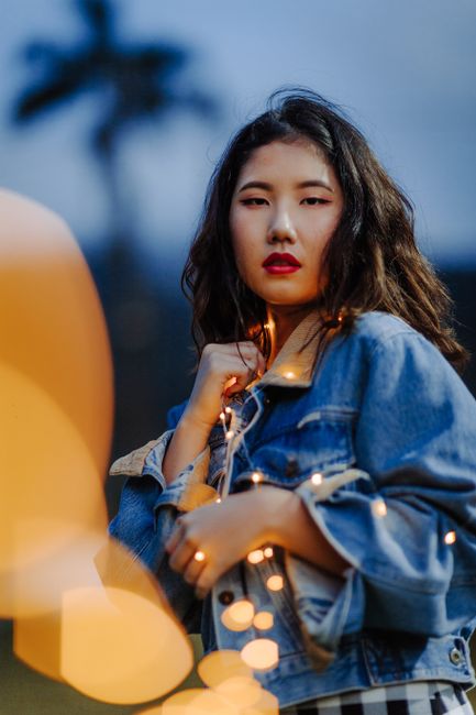 Evening portrait of a fashionable woman with lights and denim jacket creating a trendy look.