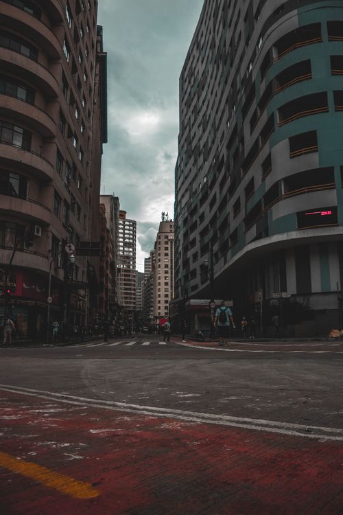 Free Moody urban scene with towering buildings and overcast sky, capturing city life. Stock Photo