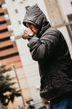 白天，一名穿着夹克的男子在城市里喝热饮