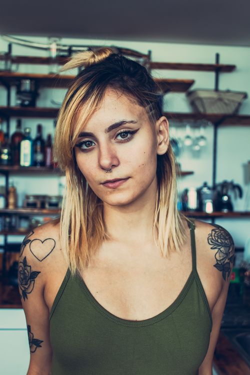 Free Close-up portrait of a tattooed young woman with blonde hair indoors, exuding confidence and style. Stock Photo
