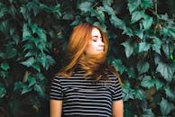 一位美丽的红发年轻女子，背靠着郁郁葱葱的绿叶