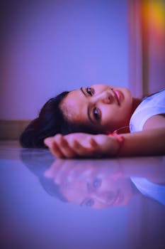 一幅描绘躺在床上女子的宁静肖像，柔和的灯光与倒影营造出梦幻般的氛围