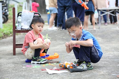 Two young boys playing with toys on the ground