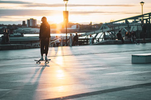 Free A person is skateboarding on a sidewalk at sunset Stock Photo