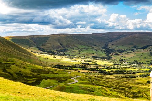 Free A picturesque view of a rural valley with rolling hills under a dynamic sky, ideal for nature enthusiasts. Stock Photo