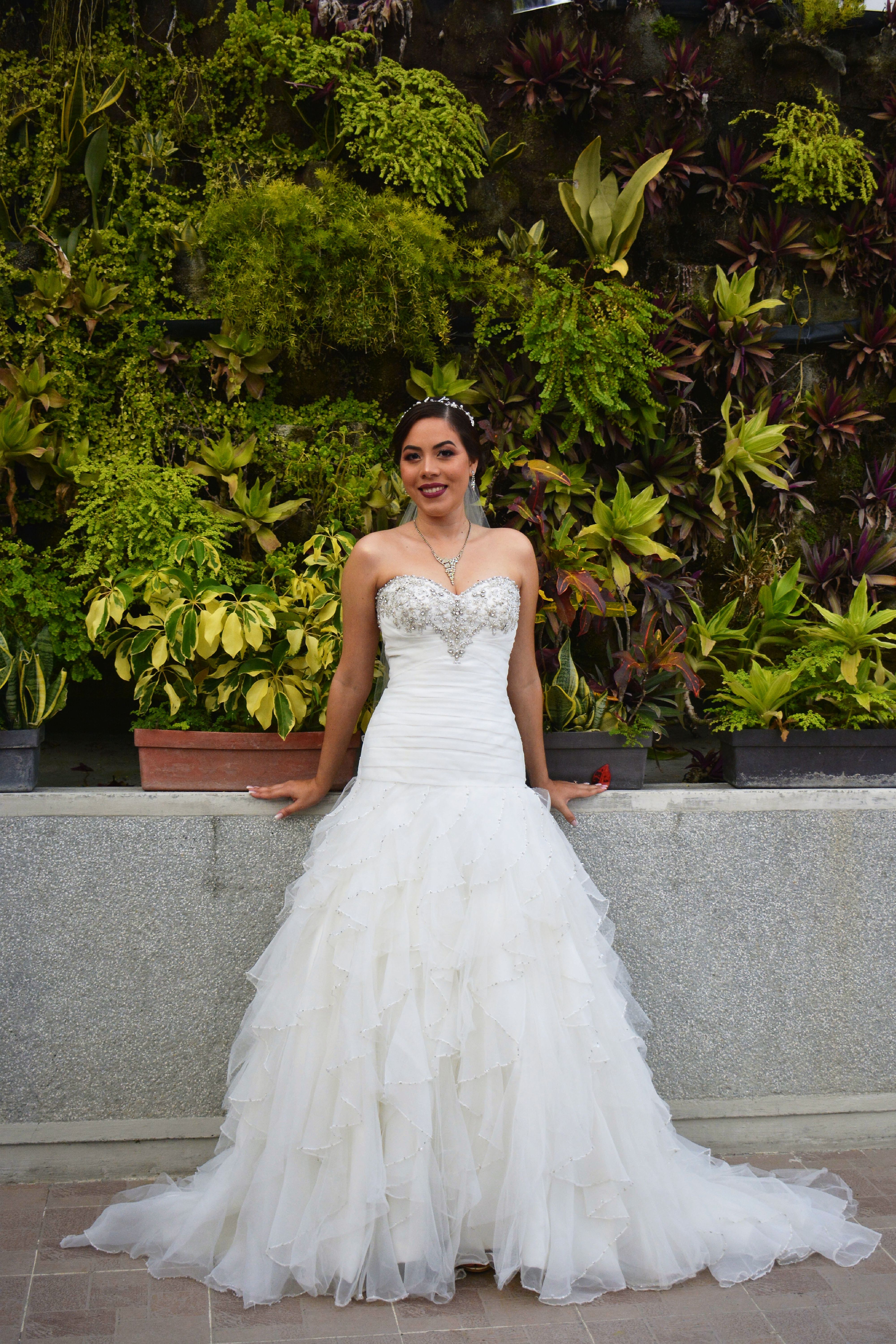 A beautiful bride in a strapless wedding dress posing in a lush garden in Barquisimeto, Venezuela.