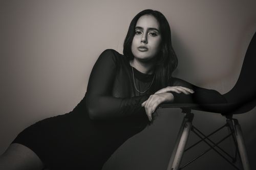 Free Elegant black and white portrait of a woman leaning on a chair in a modern setting. Stock Photo