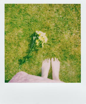 光着脚踩在郁郁葱葱的绿草上，旁边点缀着黄色花朵，这幅宁静的俯视图捕捉到了春天的精髓