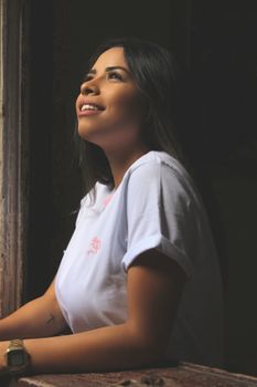 A joyful woman looks out a window with a smile, capturing a moment of happiness.