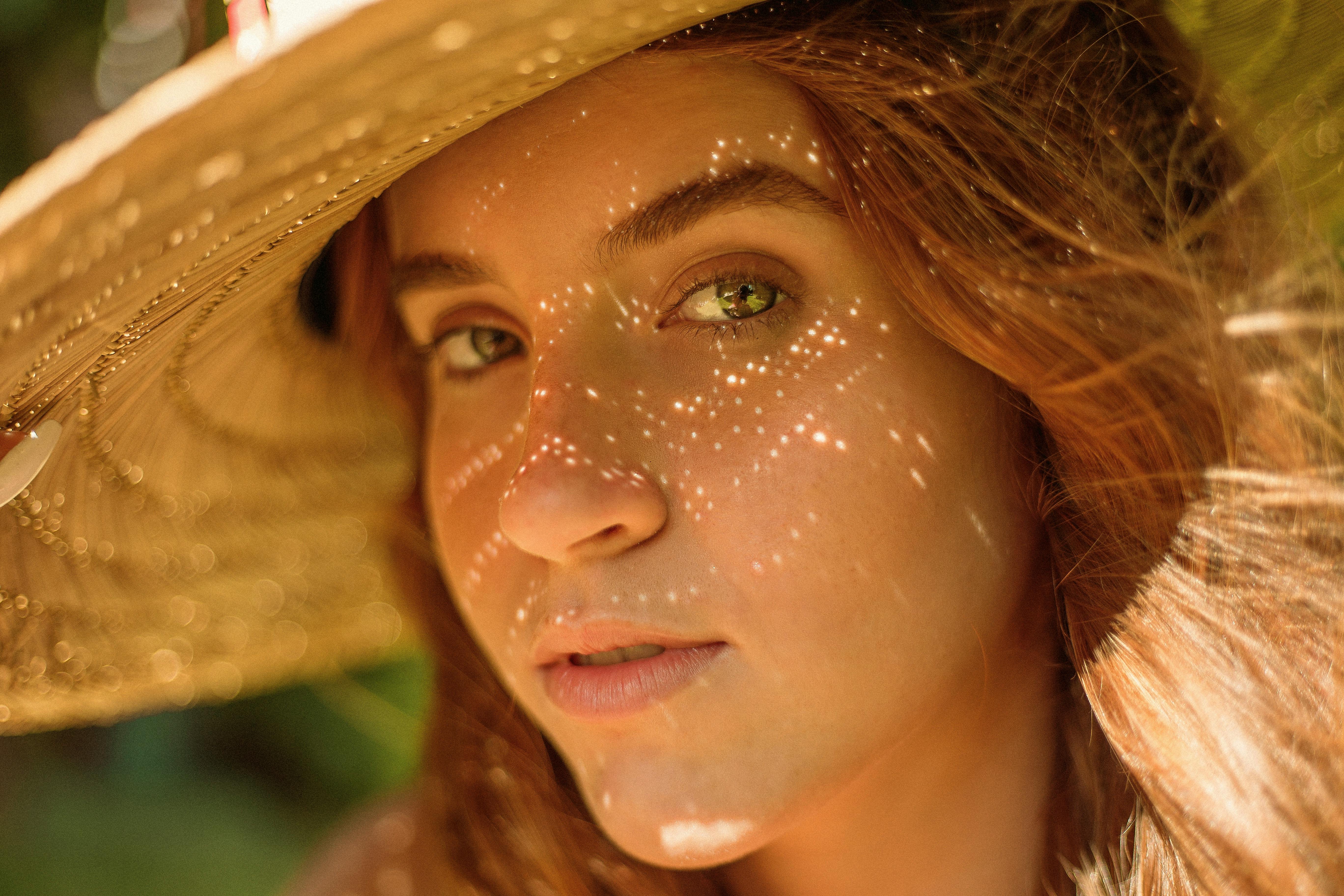 年轻女子戴着草帽的特写，营造出温暖的阴影效果