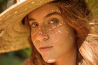 年轻女子戴着草帽的特写，营造出温暖的阴影效果