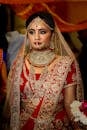 美丽的印度新娘身着红金相间的莱亨加礼服，佩戴精致珠宝，在室内优雅地摆出姿势
