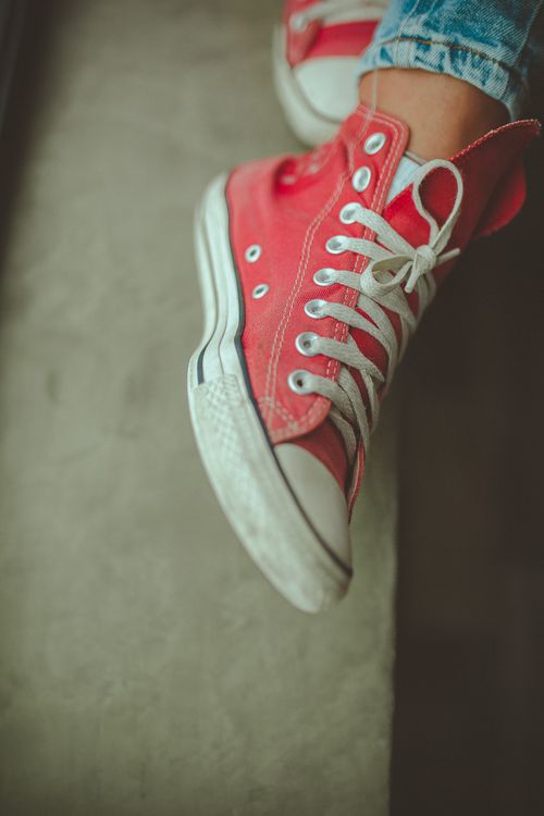 Free Stylish red sneakers with white laces and soles worn with blue jeans, showcasing casual fashion. Stock Photo