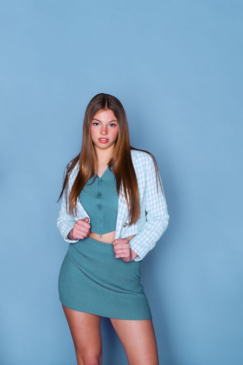 Free Portrait of a fashionable young woman in blue attire against a matching backdrop. Stock Photo