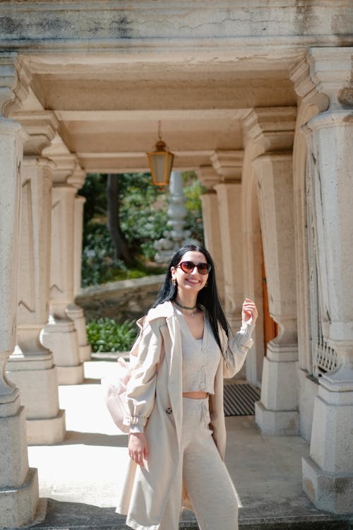 A woman in a beige outfit posing in front of an archway